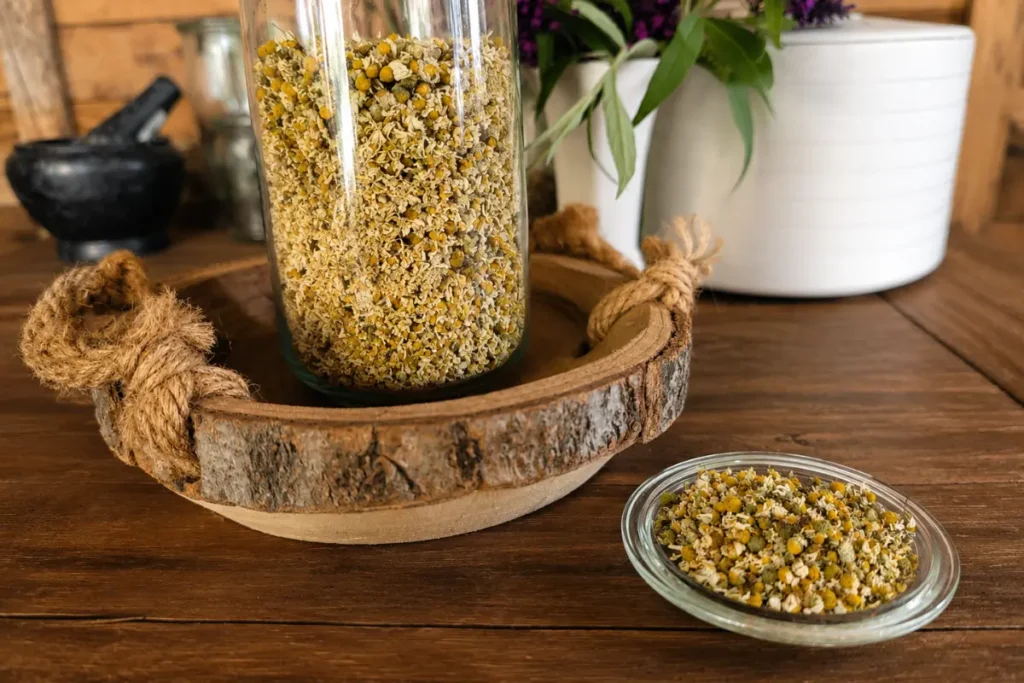 Een grote weckpot vol met natuurlijk gedroogde echte kamille bloemen. Een schoteltje met gedroogde kamille bloemen.